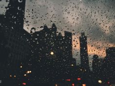 rain drops on the window and buildings in the background with a message written below it