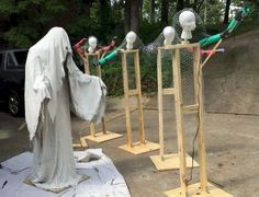 a row of wooden poles with heads on them in front of a parking lot filled with cars