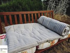 a mattress on a wooden bench in the grass