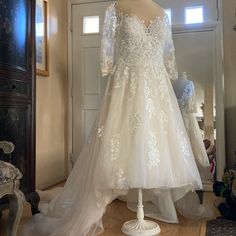 a wedding dress is displayed on a mannequin in front of a mirror,