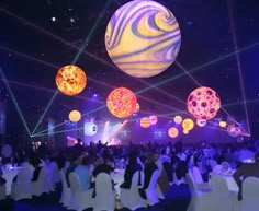 a large group of people sitting at tables in front of a stage with lights on it