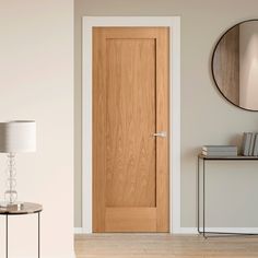 an empty room with a wooden door in the middle and a lamp on the side table next to it