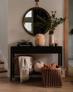 a black table topped with two pumpkins and a mirror