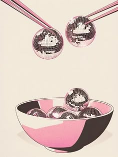 an image of disco balls in a bowl with chopsticks flying above it and the reflection of them