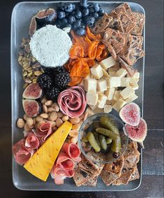 an assortment of cheeses, crackers, fruits and nuts on a platter