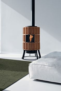 a bed with a white sheet and a wood burning stove in the corner next to it