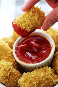 someone dipping something into a small bowl with ketchup on it in the middle of some fried food