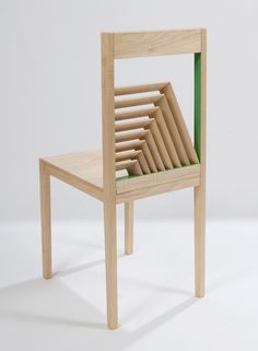 a wooden chair sitting on top of a white floor next to a green object in the middle