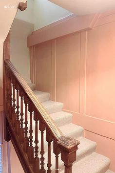 a stair case in the corner of a room with pink walls and carpeted stairs