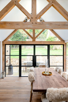 a large wooden table sitting in the middle of a room with glass doors leading to an outside patio