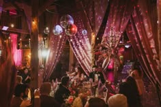 a group of people that are standing in the middle of a room with disco balls