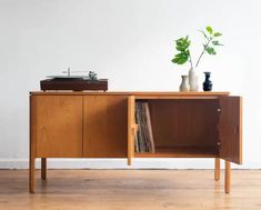 a record player sitting on top of a wooden cabinet next to a potted plant