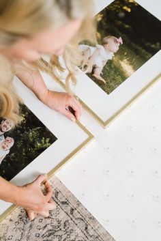 a woman is looking at photos on a table with a calendar in front of her