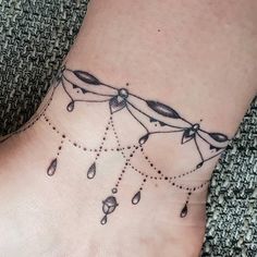 a woman's foot with a tattoo on the ankle and beads hanging from it