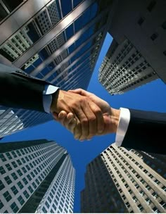 two men shaking hands in front of tall buildings