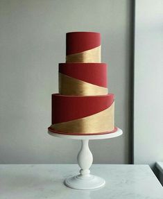 a three tiered cake sitting on top of a white table next to a window