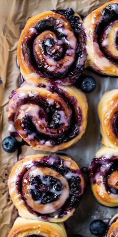 blueberry cinnamon rolls with icing sitting on top of brown paper