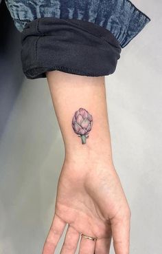 a small pink flower tattoo on the wrist