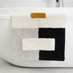 a white toilet with black and grey squares on it's side next to a bathtub