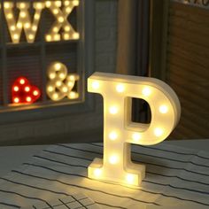 a light up letter sitting on top of a table next to a window with lights