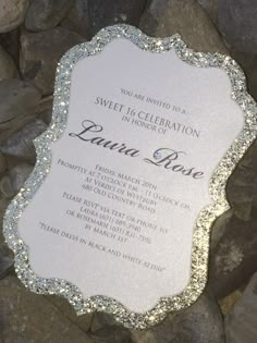 a white and silver wedding card sitting on top of some rocks with the words sweet celebration in it