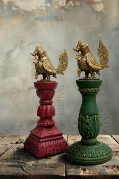 two red and green vases sitting on top of a wooden table next to each other