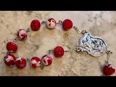 a red and white beaded bracelet on a marble surface