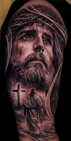 a man with a cross and jesus tattoo on his arm, in black and grey