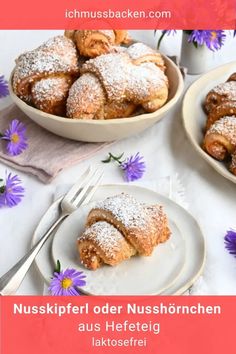 two plates with pastries on them next to a bowl of powdered doughnuts