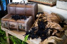 two pieces of luggage sitting on top of a wooden table next to ferns and leaves