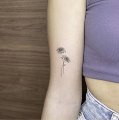 a woman's arm with a single flower tattoo on the left side of her right arm