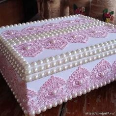 a pink and white cake with pearls on it