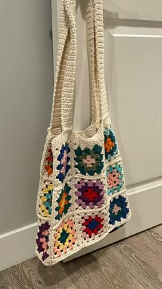 a crocheted bag hanging on the wall next to a door with a handle