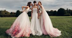 three beautiful women standing next to each other in a field