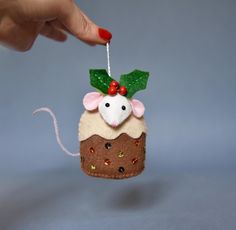 a hand is holding a christmas ornament that looks like a cupcake with a mouse on top