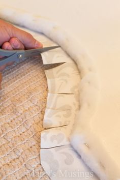 a person cutting fabric with scissors on top of a piece of material that has been cut