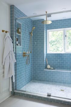 a blue tiled bathroom with a shower and bathtub in the corner, next to a window