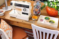 a sewing machine sitting on top of a wooden table next to a vase filled with flowers