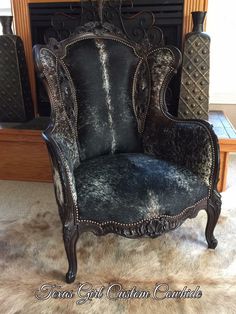 an ornate black chair sitting in front of a fire place with fur on the floor