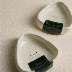 two black and white ceramic bowls with faces on them sitting on a carpeted floor