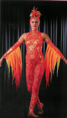 a woman in an orange and yellow costume with large feathers on her head, arms and legs