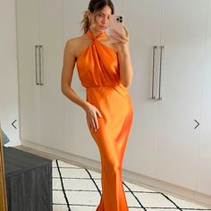 a woman in an orange dress taking a selfie