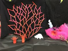 the table is covered with black and pink paper, orange sticks, and other decorations