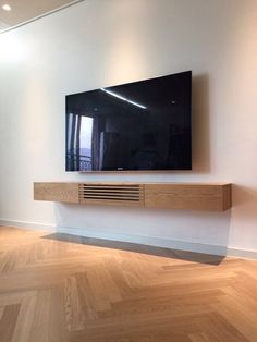 a flat screen tv mounted to the side of a wall in an empty living room