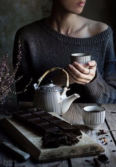 a woman is holding a teapot and some chocolate