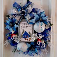 a blue and white christmas wreath hanging on the front door with reindeer ornaments around it