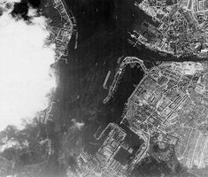 black and white photograph of an aerial view of a city from the air, looking down