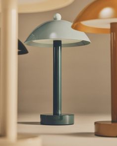 two lamps sitting on top of a table next to each other, one light blue and the other white