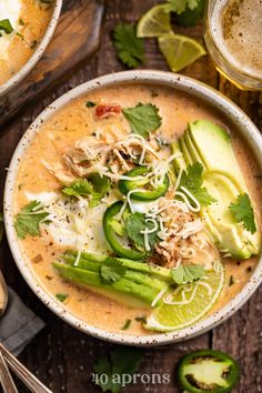 a white bowl filled with soup and garnished with cilantro, avocado, sour cream and parmesan cheese