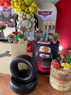 there are many balloons and decorations in the room with cars on display at this birthday party